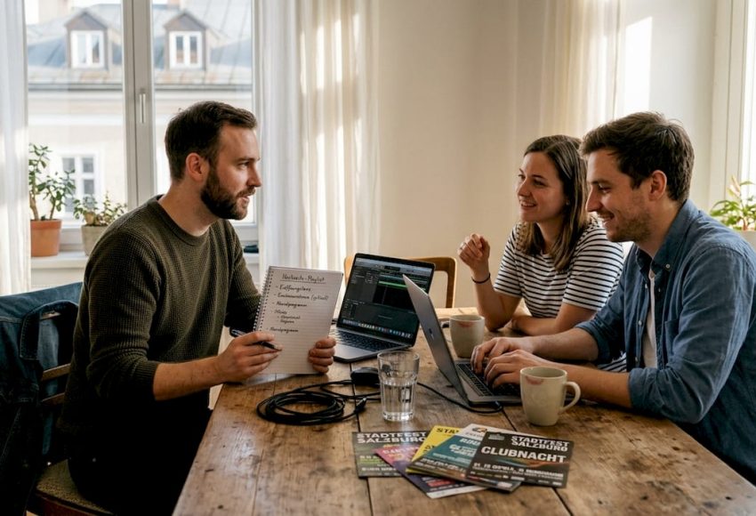 Ein DJ und ein Paar sitzen gemeinsam in ihrer Salzburger Wohnung und schmieden Pläne für eine bevorstehende Veranstaltung.