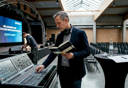 Bevor die Konferenz beginnt, überprüft der Veranstaltungsleiter das Mischpult, um einen reibungslosen Ablauf zu gewährleisten.