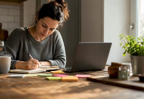 Eine Frau stellt vom heimischen Schreibtisch aus am Laptop ein Event-Paket zusammen.