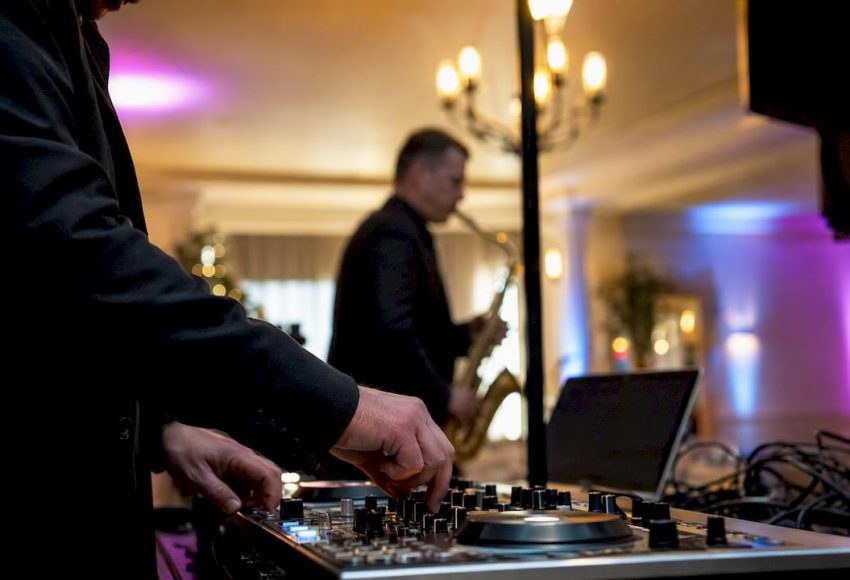 DJ und Saxophonist bauen gemeinsam ihr Equipment für die bevorstehende Veranstaltung auf.