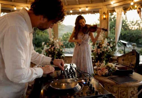 Ein DJ feilt an den Einstellungen seines Mischpults, während eine Violinistin ihre Geige stimmt.