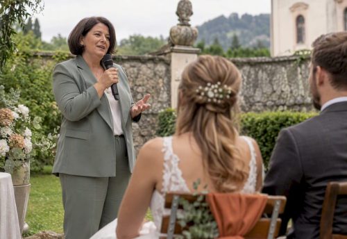 Die Traurednerin spricht bei der Gartenhochzeit ins drahtlose Mikrofon.
