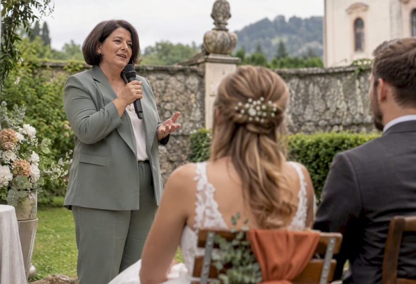 Die Traurednerin spricht bei der Gartenhochzeit ins drahtlose Mikrofon.